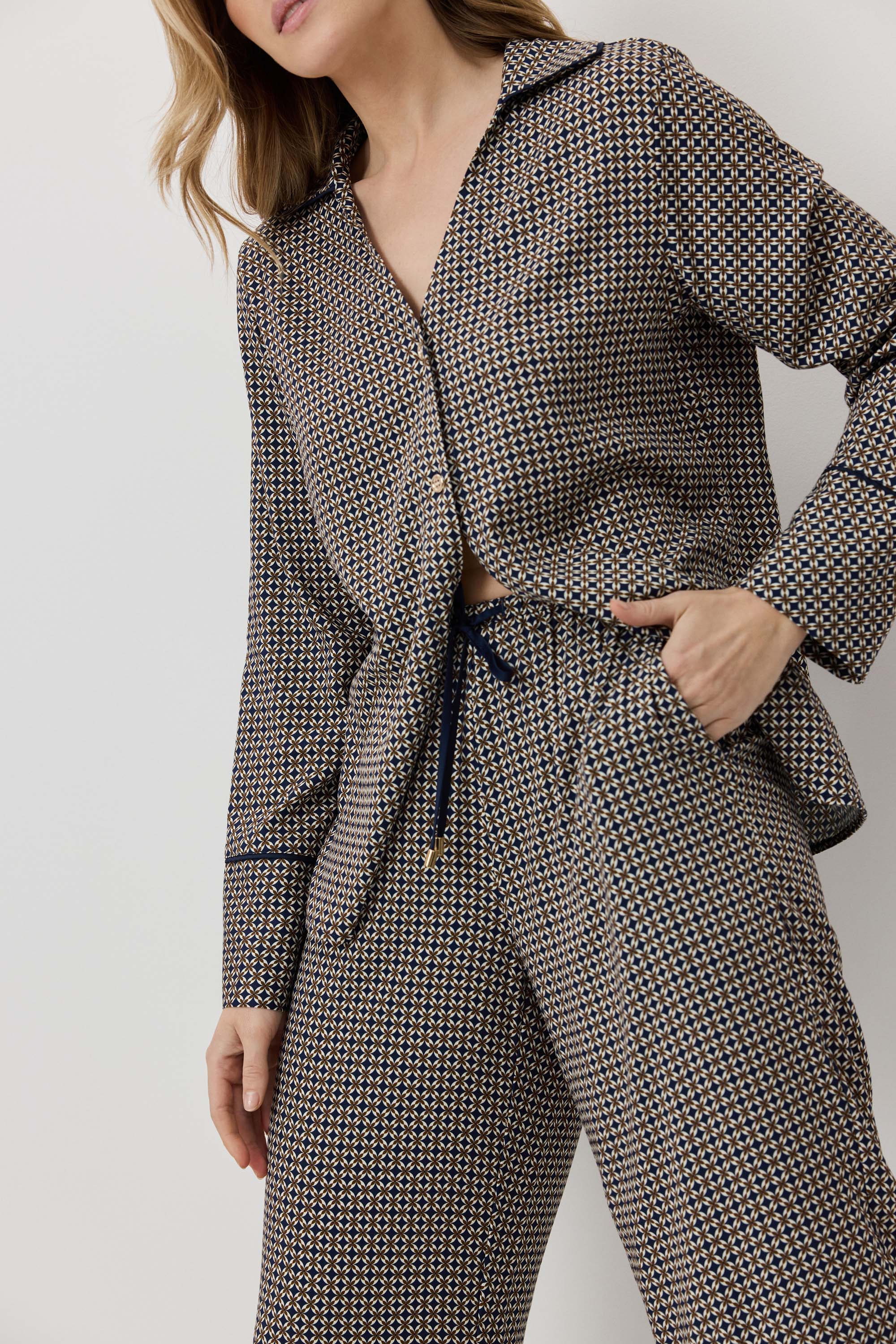 Woman wearing a houndstooth patterned outfit with a belt on a plain background