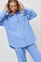 Woman wearing a light blue pajama set against a plain background
