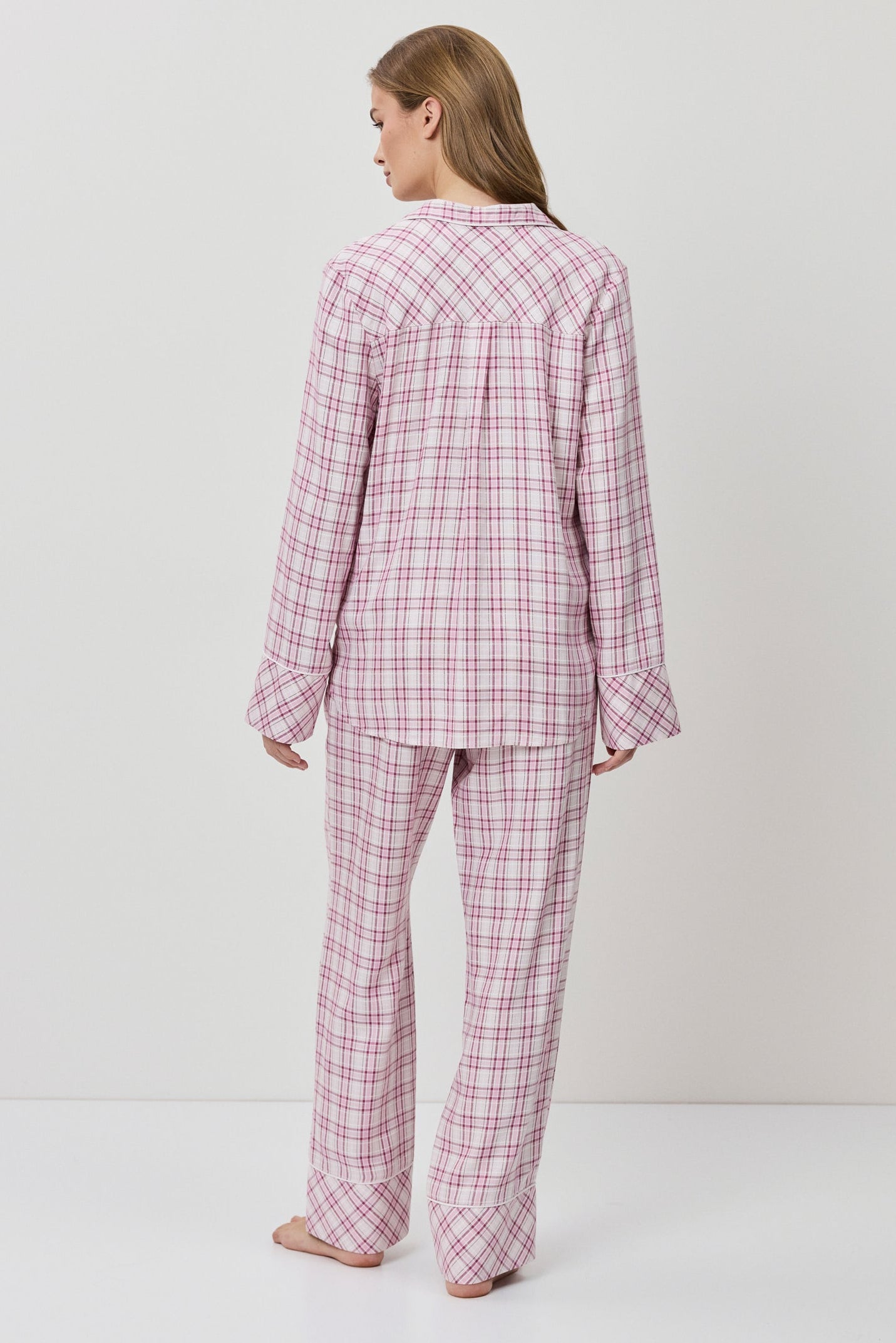 Person wearing pink checkered pajamas on a white background