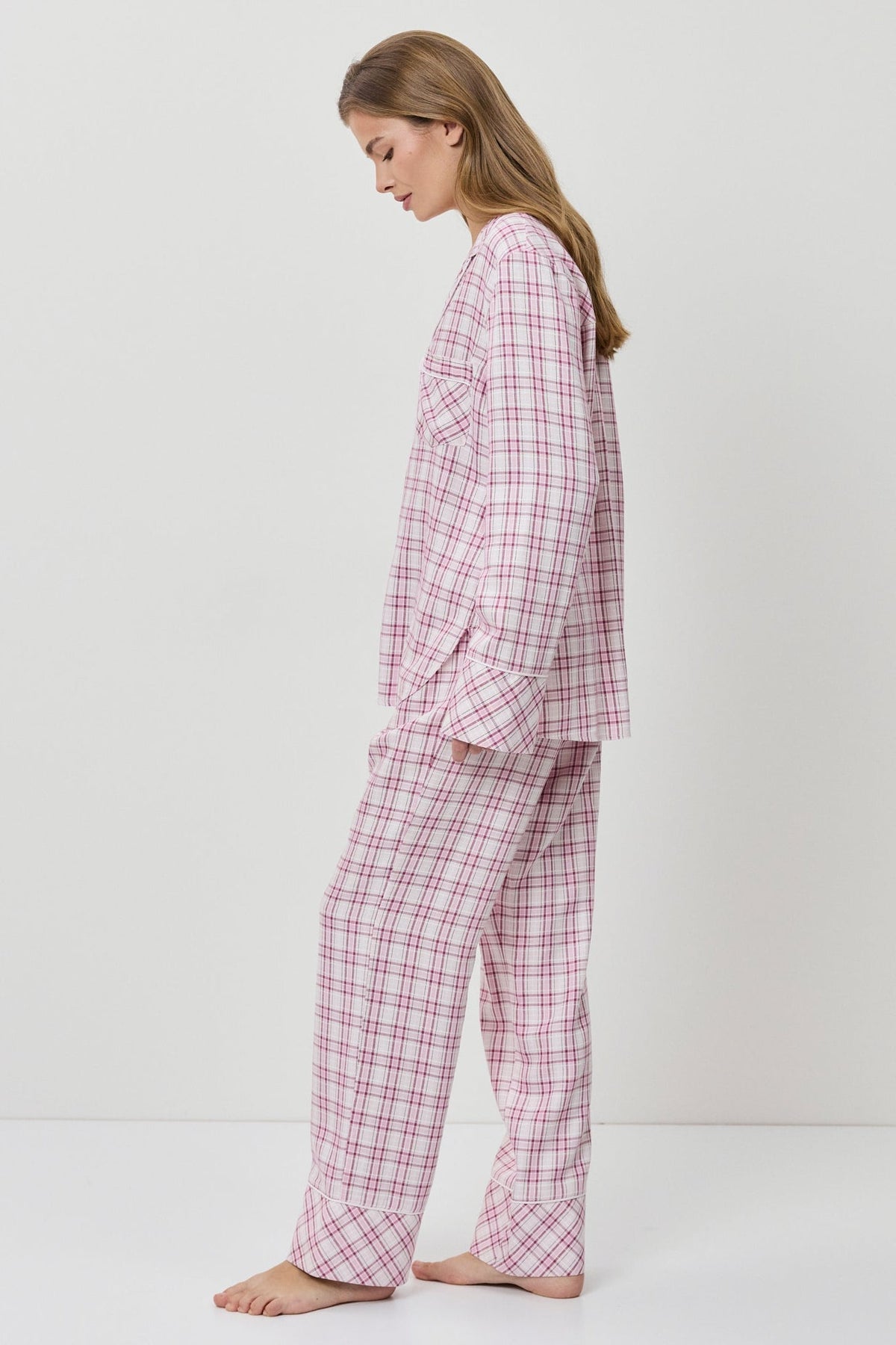 Woman wearing pink checkered pajamas on a white background