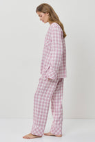 Woman wearing pink checkered pajamas on a white background
