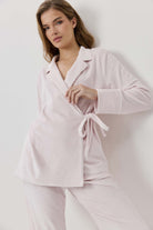 Woman wearing a light pink pajama set against a white background