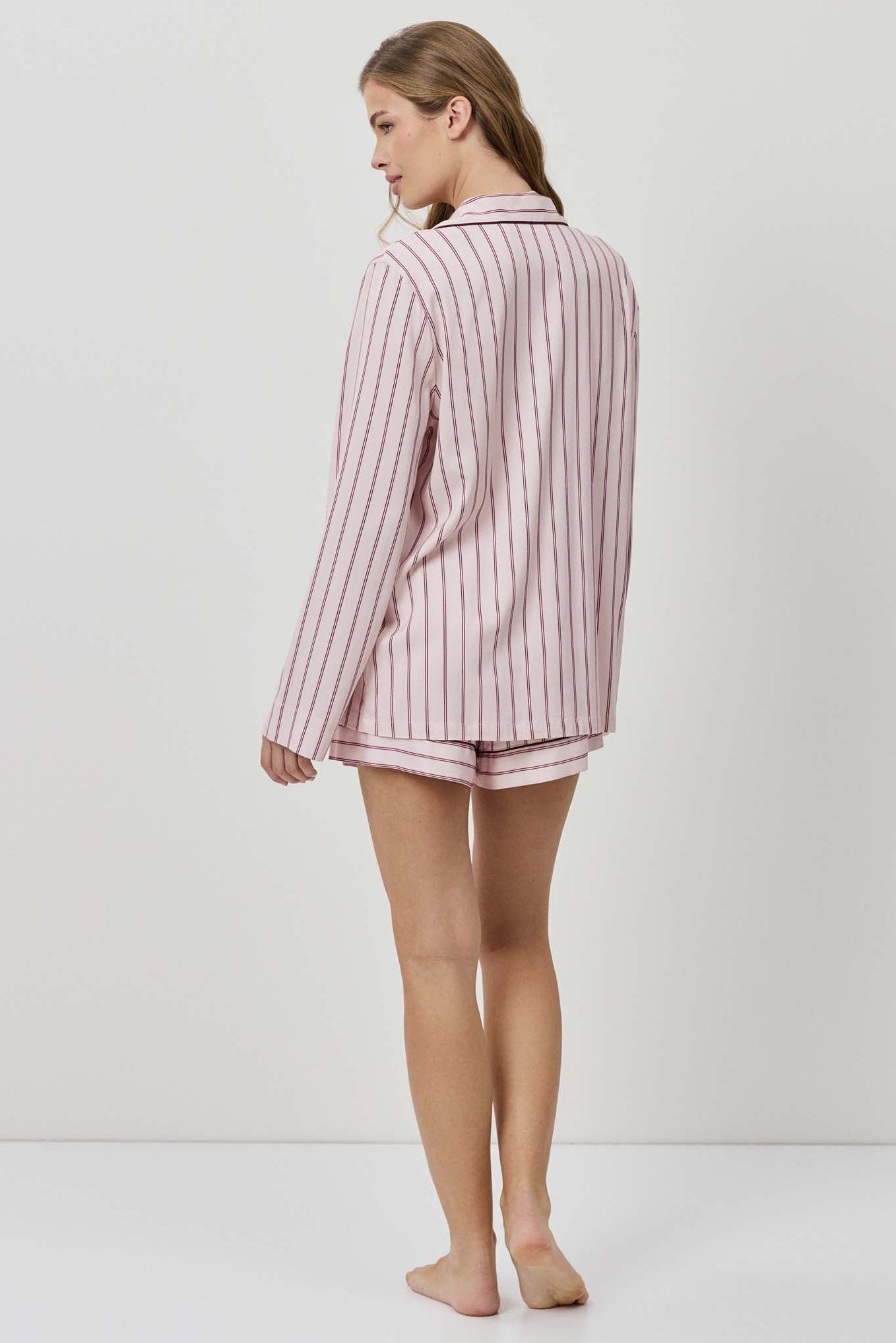 Woman wearing a pink striped pajama set on a white background