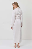 Woman wearing a white robe against a plain background