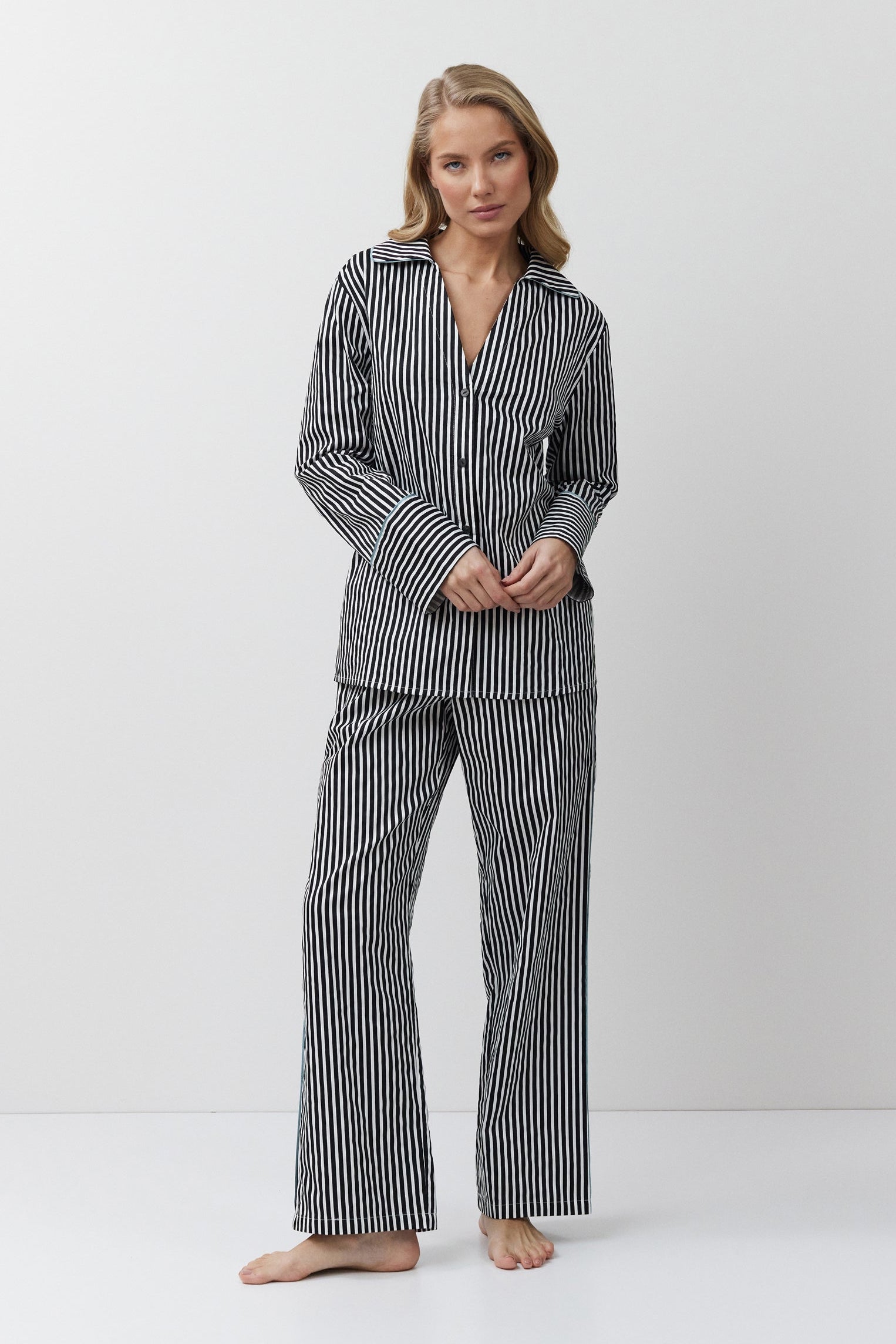 Woman wearing a black and white striped pajama set on a white background