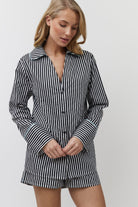 Woman wearing a black and white striped shirt and shorts on a plain background