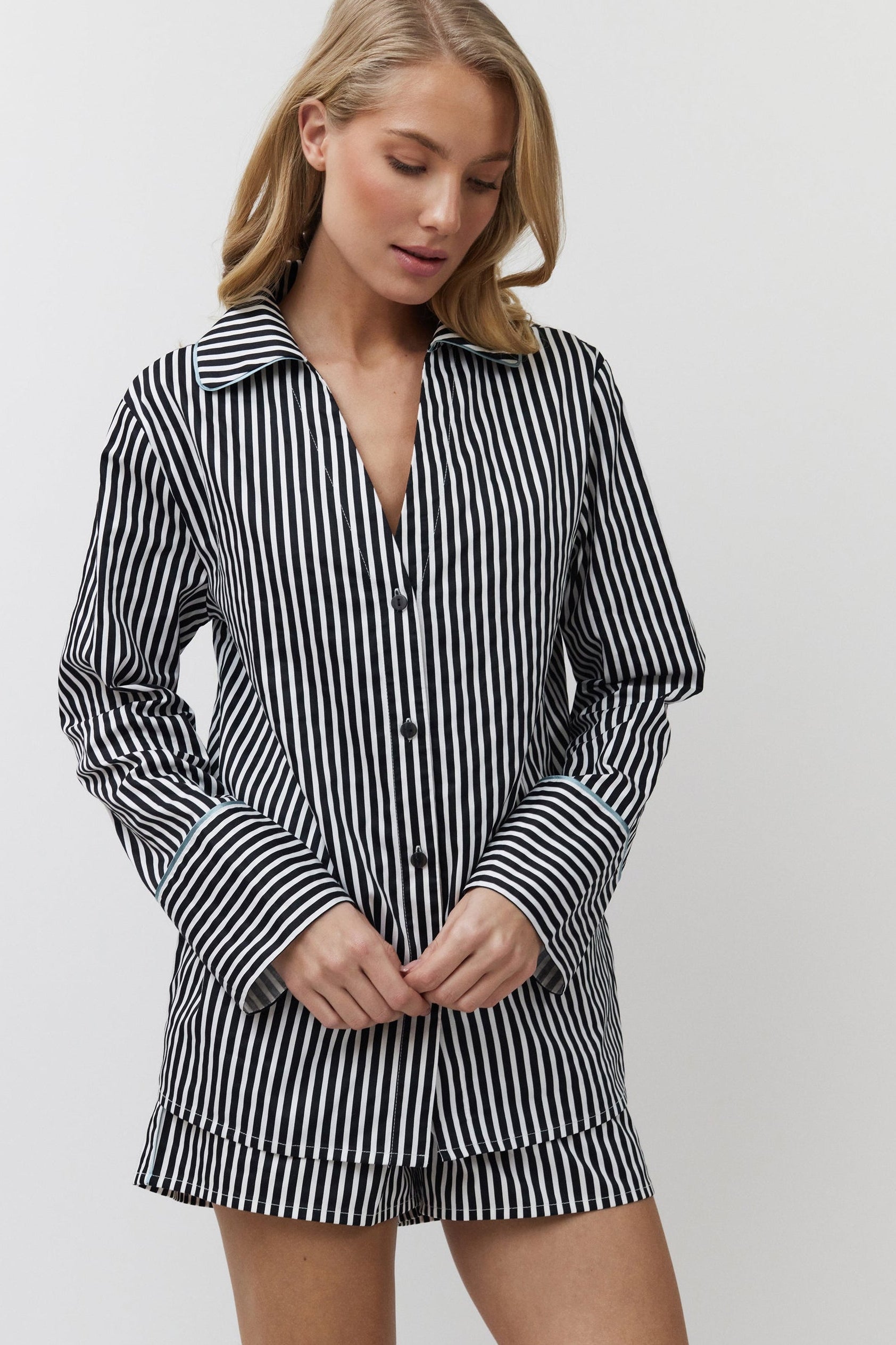 Woman wearing a black and white striped shirt and shorts on a plain background