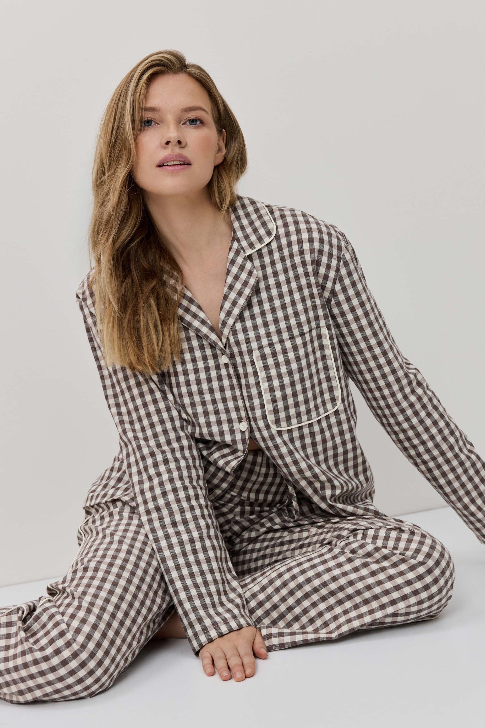 Woman wearing a checkered pajama set on a plain background