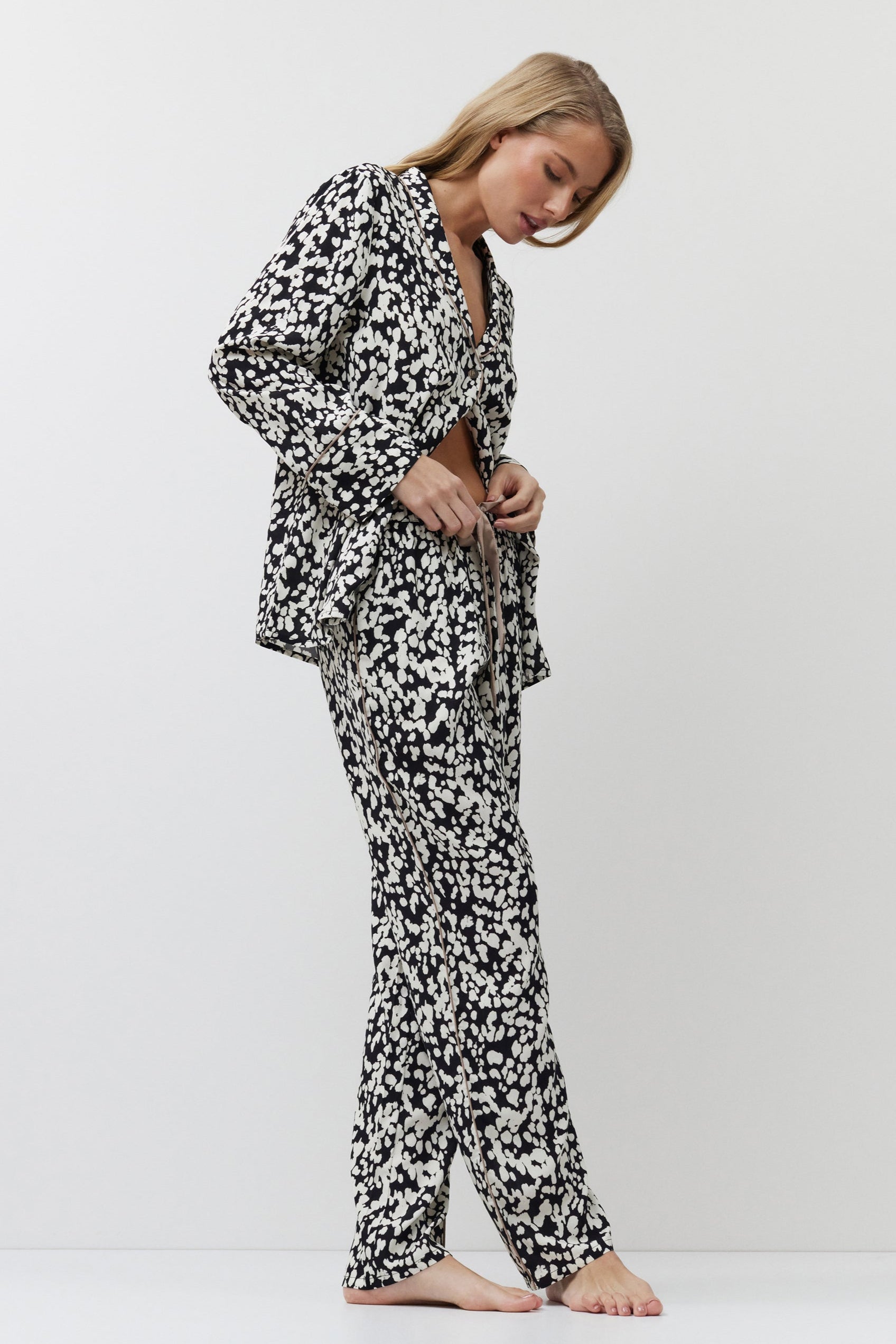 Woman wearing a black and white patterned pajama set on a white background