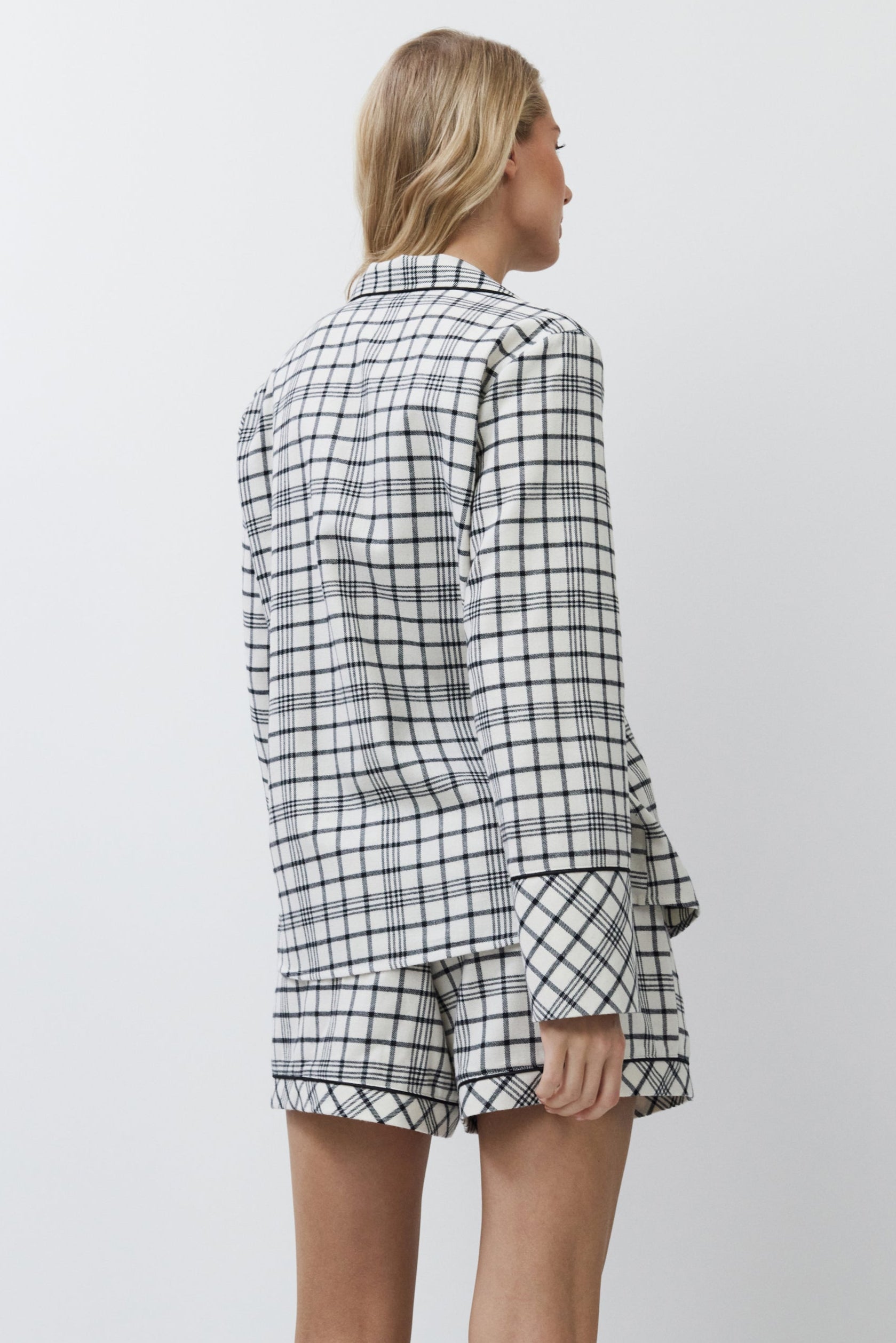 Woman wearing a checkered shirt and shorts set on a white background