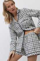 Woman wearing a black and white checkered pajama set on a plain background