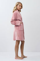 Woman wearing a pink bathrobe against a white background