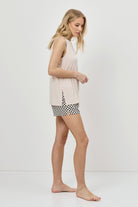 Woman wearing a sleeveless top and patterned shorts on a white background