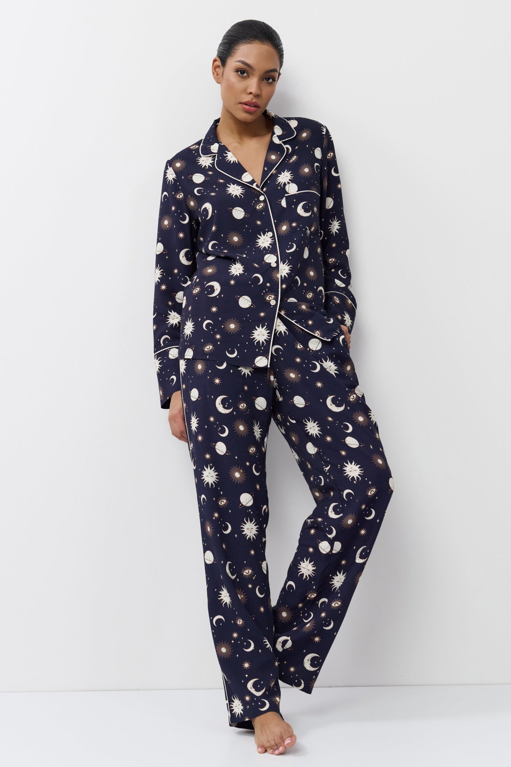 Woman wearing a navy blue pajama set with pattern on a white background