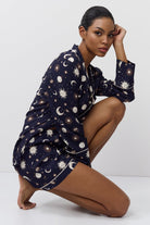 Woman wearing a navy blue pajama set with celestial pattern on a white background