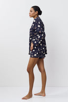 Woman wearing a navy blue pajama set with pattern on a white background