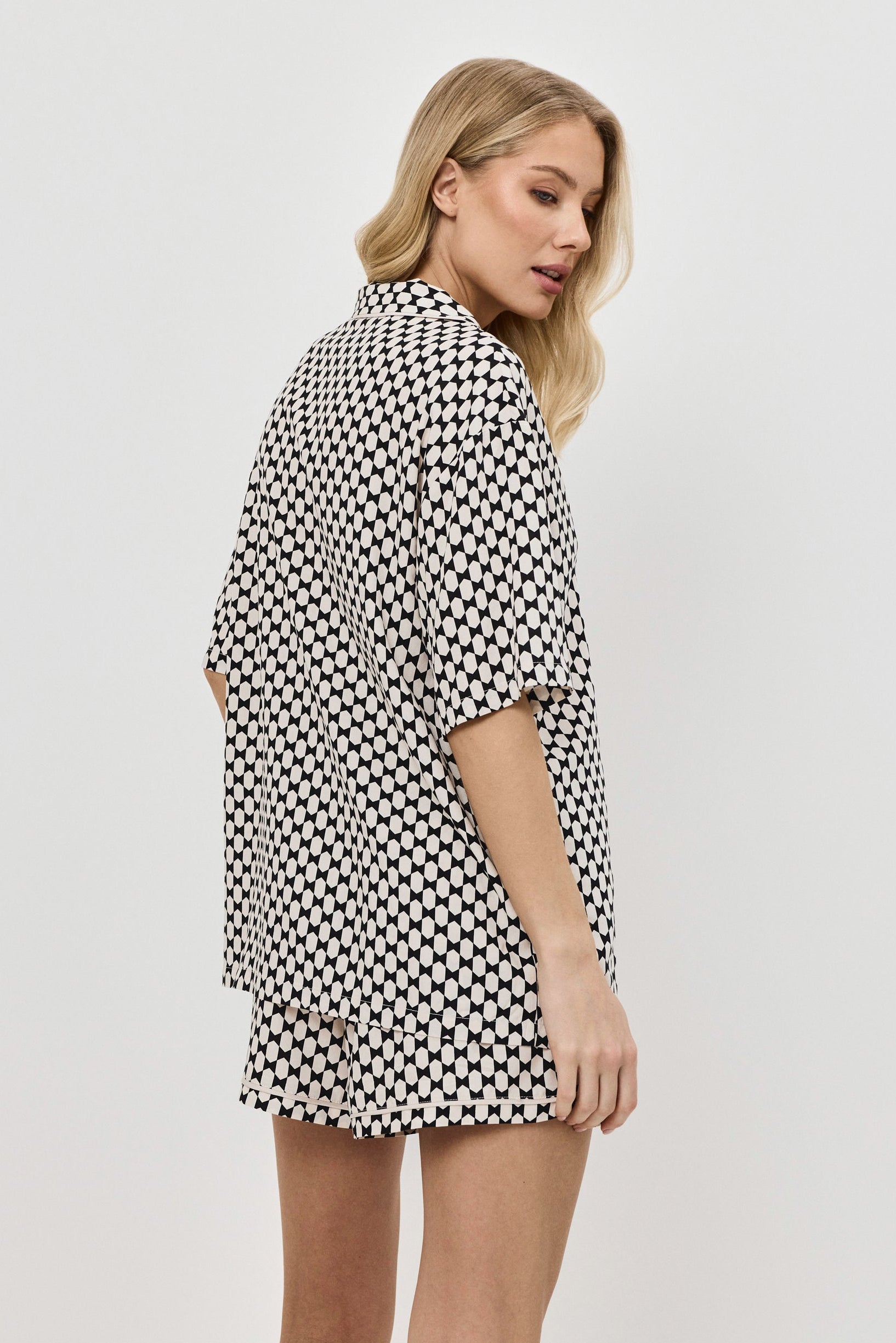 Woman wearing a patterned pajama set on a plain background