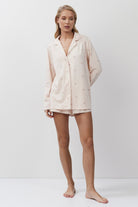Woman wearing a pijnk pajama set against a white background