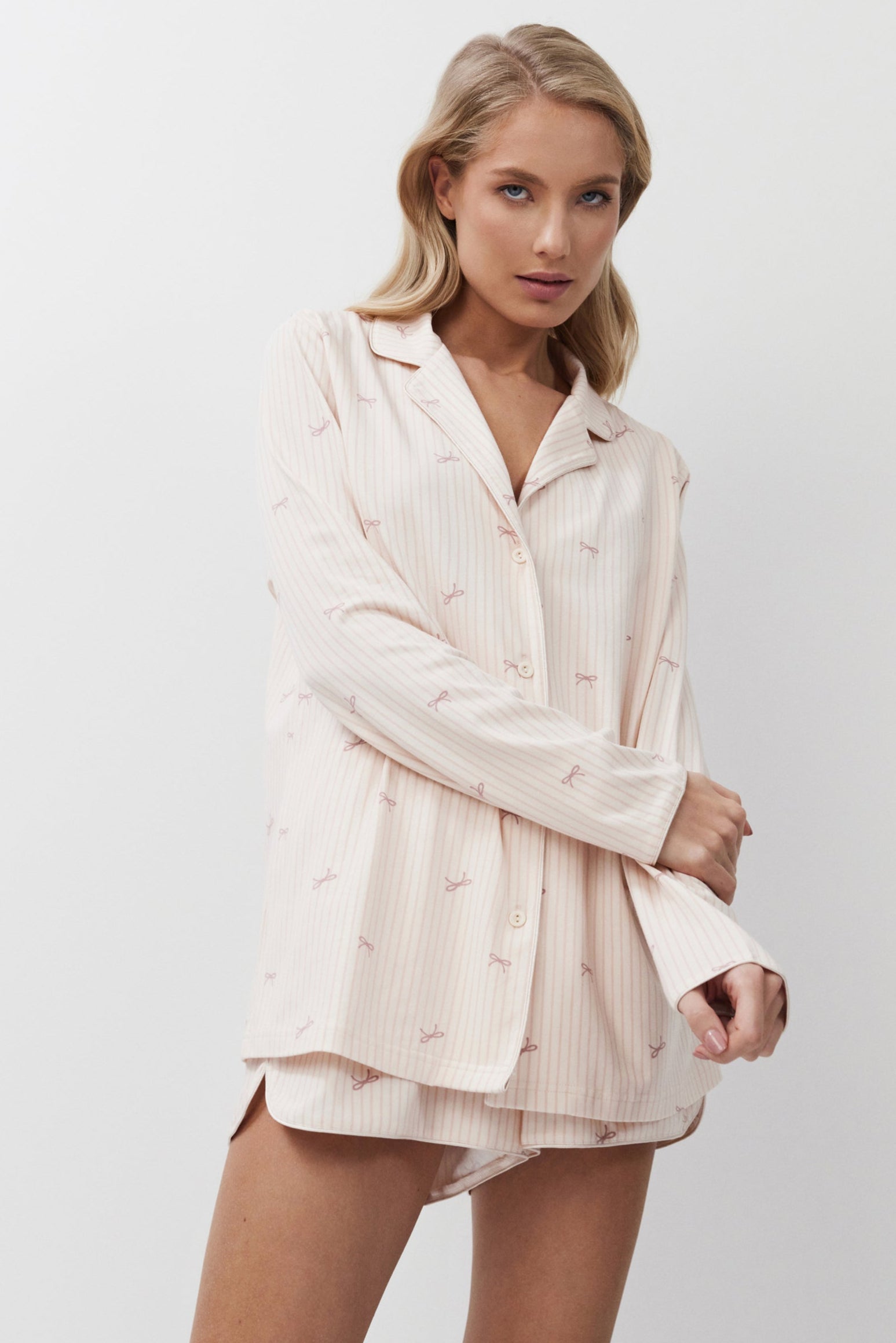 Woman wearing a light pink pajama set against a white background
