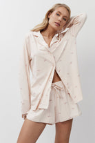 Woman wearing a light pink pajama set on a white background