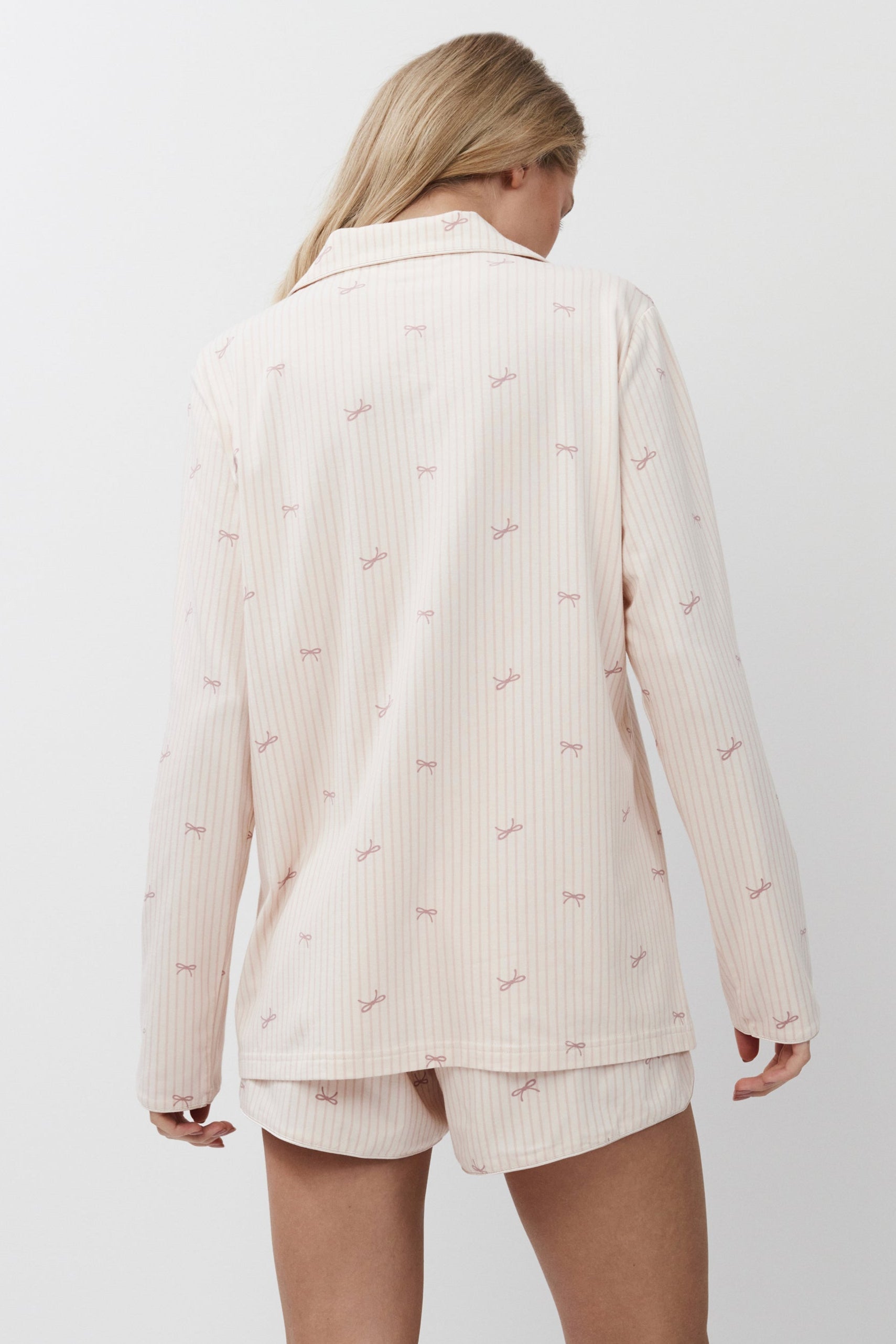 Person wearing a pink-colored pajama set on a white background