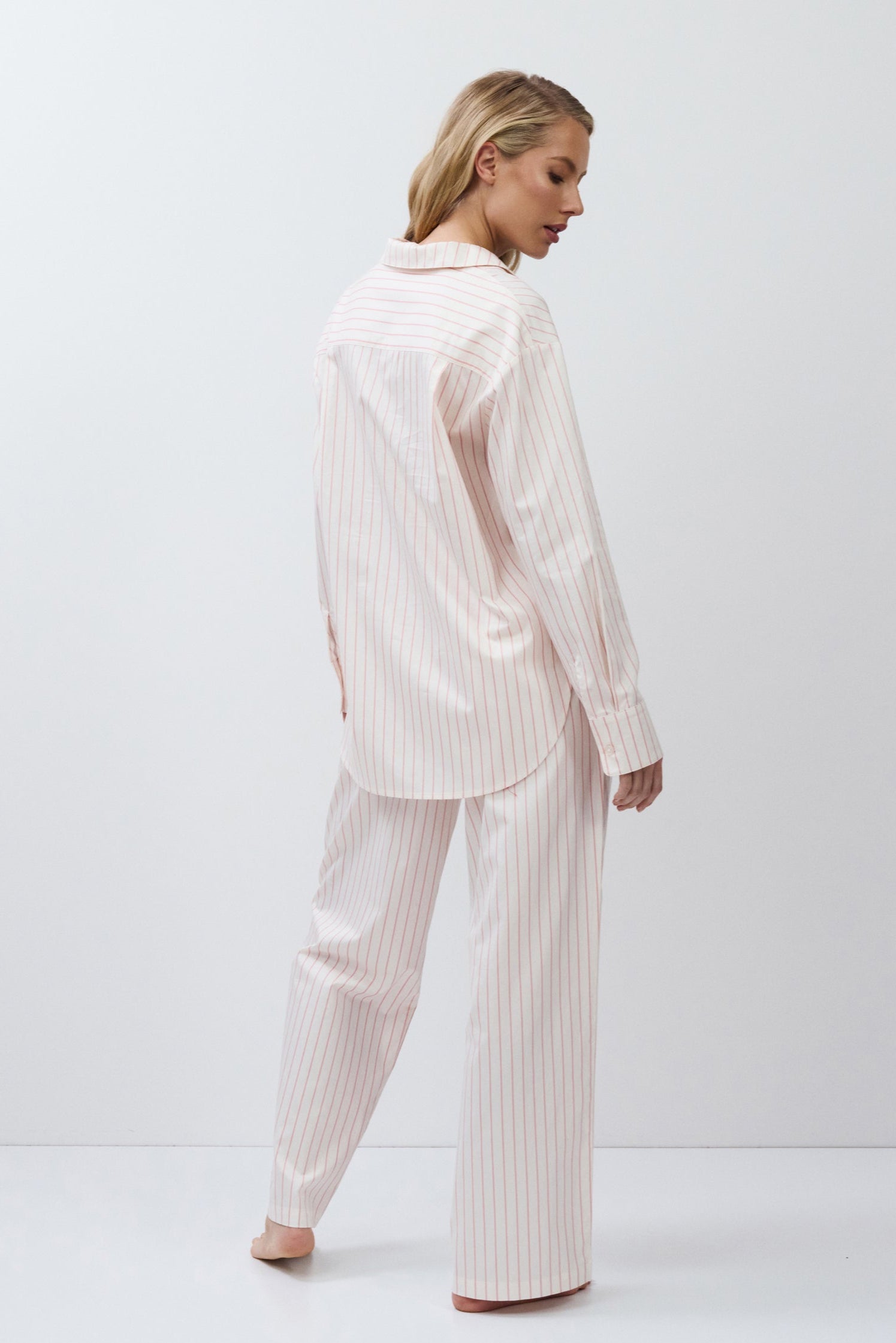 Woman wearing a light pink pajama set against a white background