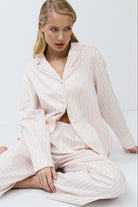 Woman wearing a striped pajama set sitting on a white floor.